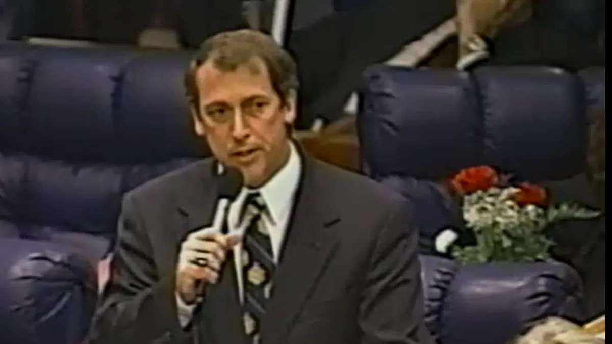 Randy Ball as a Florida state legislator, speaking from the chamber floor with a microphone.