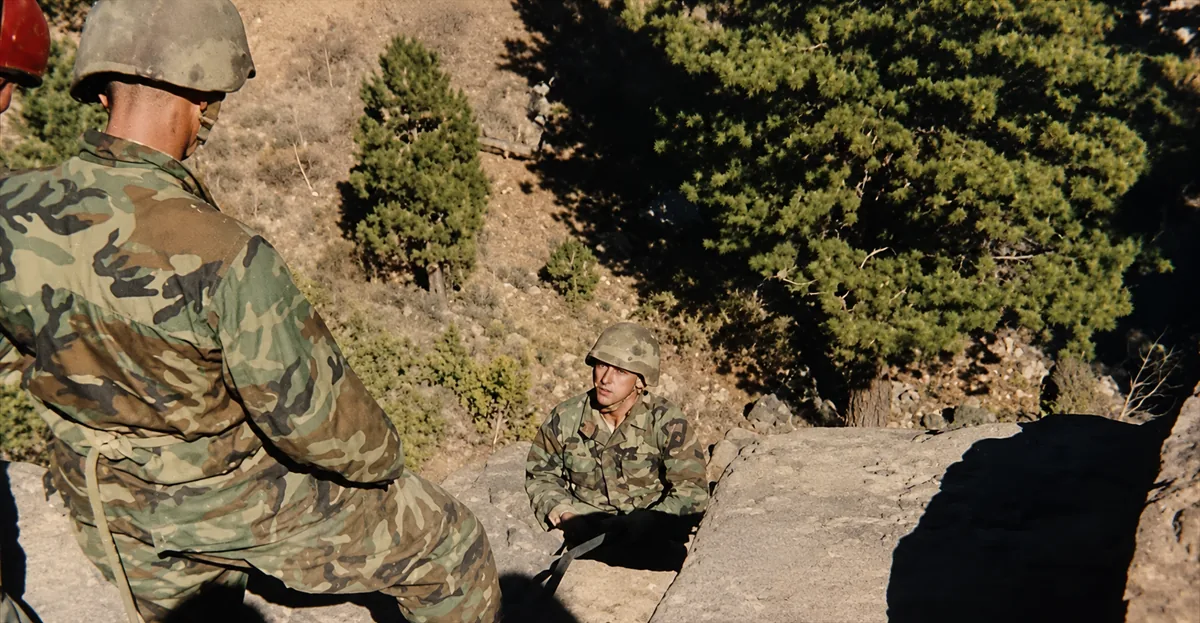 Marines in camouflage uniforms training in mountain warfare on a rocky ridge.